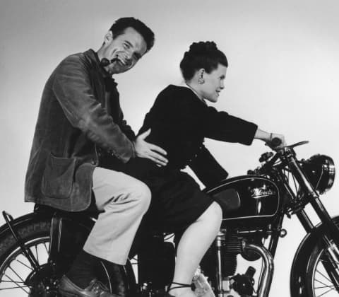 Charles and Ray Eames riding a motorcycle