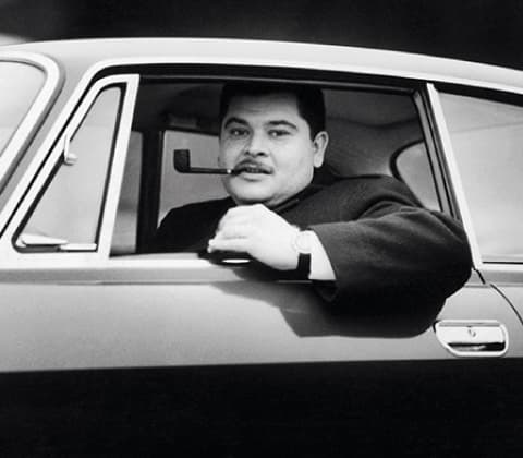A portrait of Joe Colombo smoking a pipe inside his car